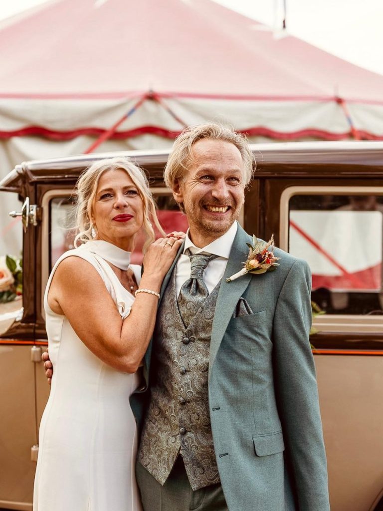 Paar lächelnd vor dem Brauttaxi Braut und Bräutigam posieren lächelnd vor dem Brauttaxi